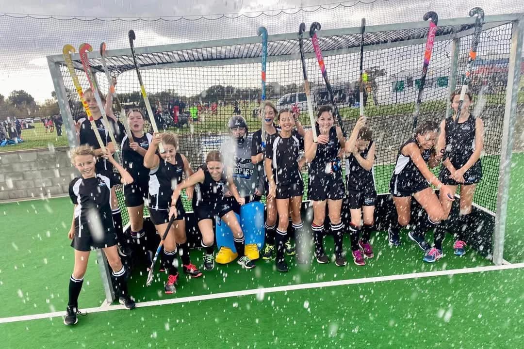 A junior Magpies team sheltering by the goal in the rain