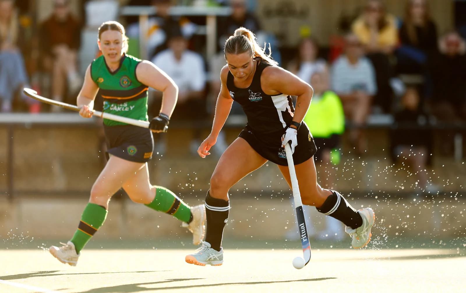 A Magpies player driving the ball past an opponent